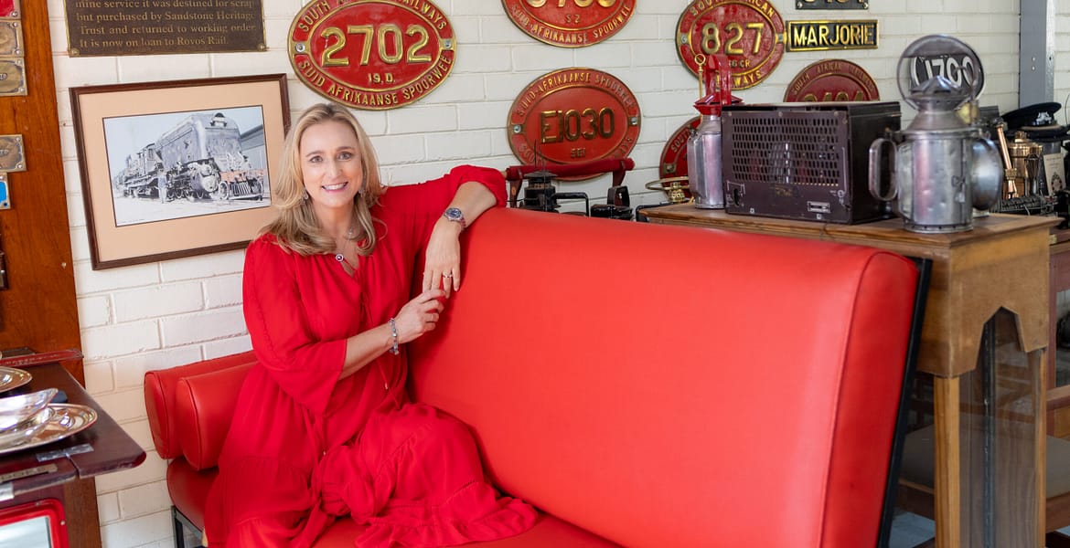 Lady in red dress sitting on a red coach at Rovos Rail's museum