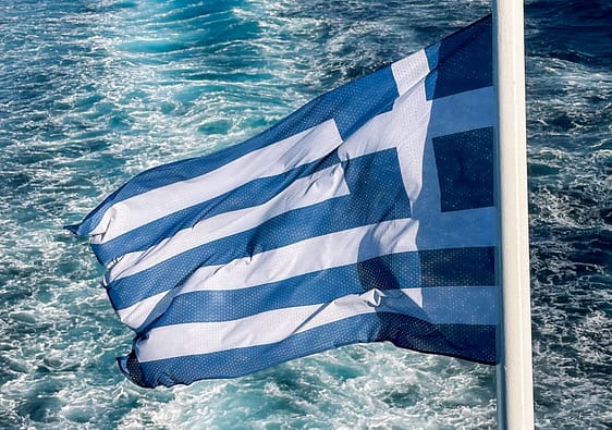 The wake of the water behind the ferry with Greek Flag