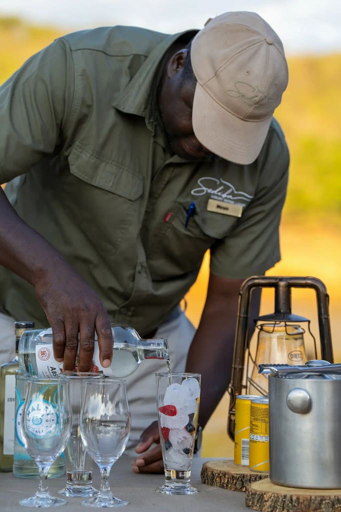 A game ranger serving guests drinks at Sediba Safari Lodge