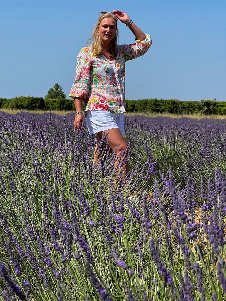 A lady standing in the French lavender fields wearing white shorts and flowery top