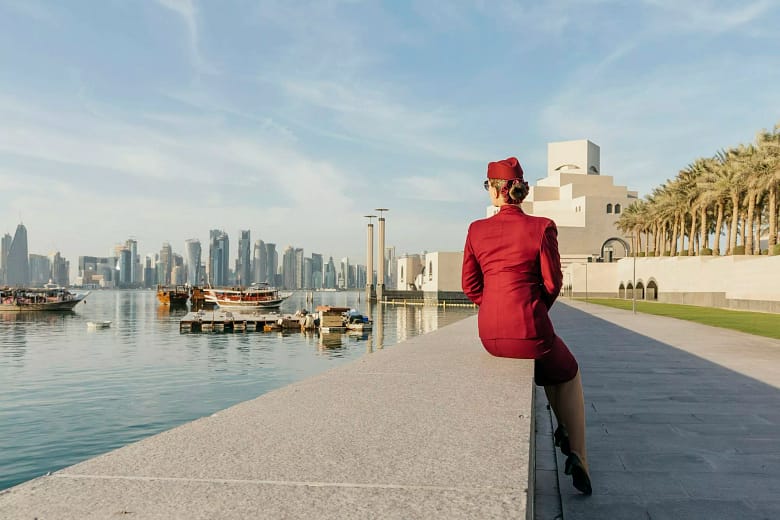 Travel hacks form Qatar crew. View from the back at unrecognisable cabin crew, looking at the skyline of Doha, Qatar, sunny day